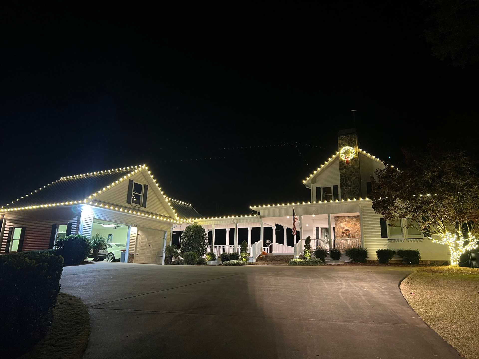 Wrapped tree and home shining with holiday lights