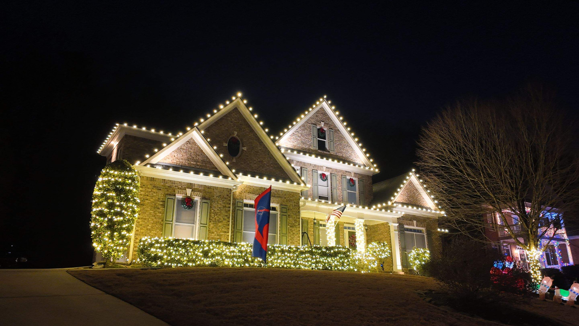 Large brick home with full roofline and landscape Christmas lighting